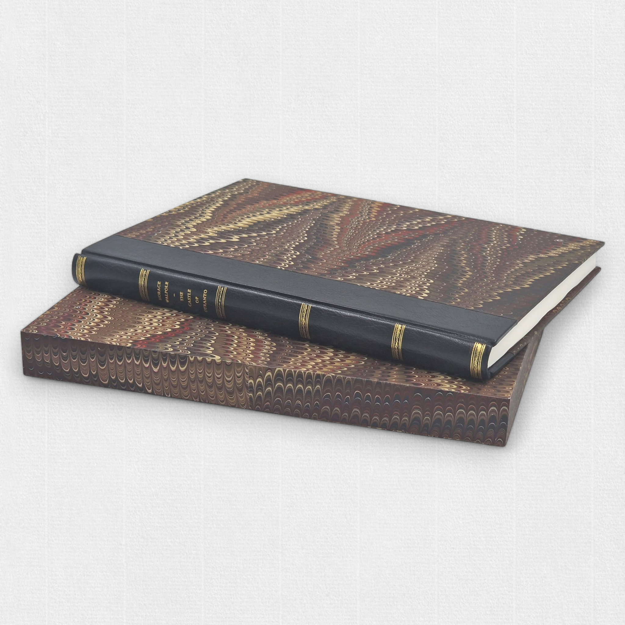 Fine press edition of The Castle of Otranto by Woodbank Press resting on a custom marbled slipcase, bound in half leather with gilt tooling.