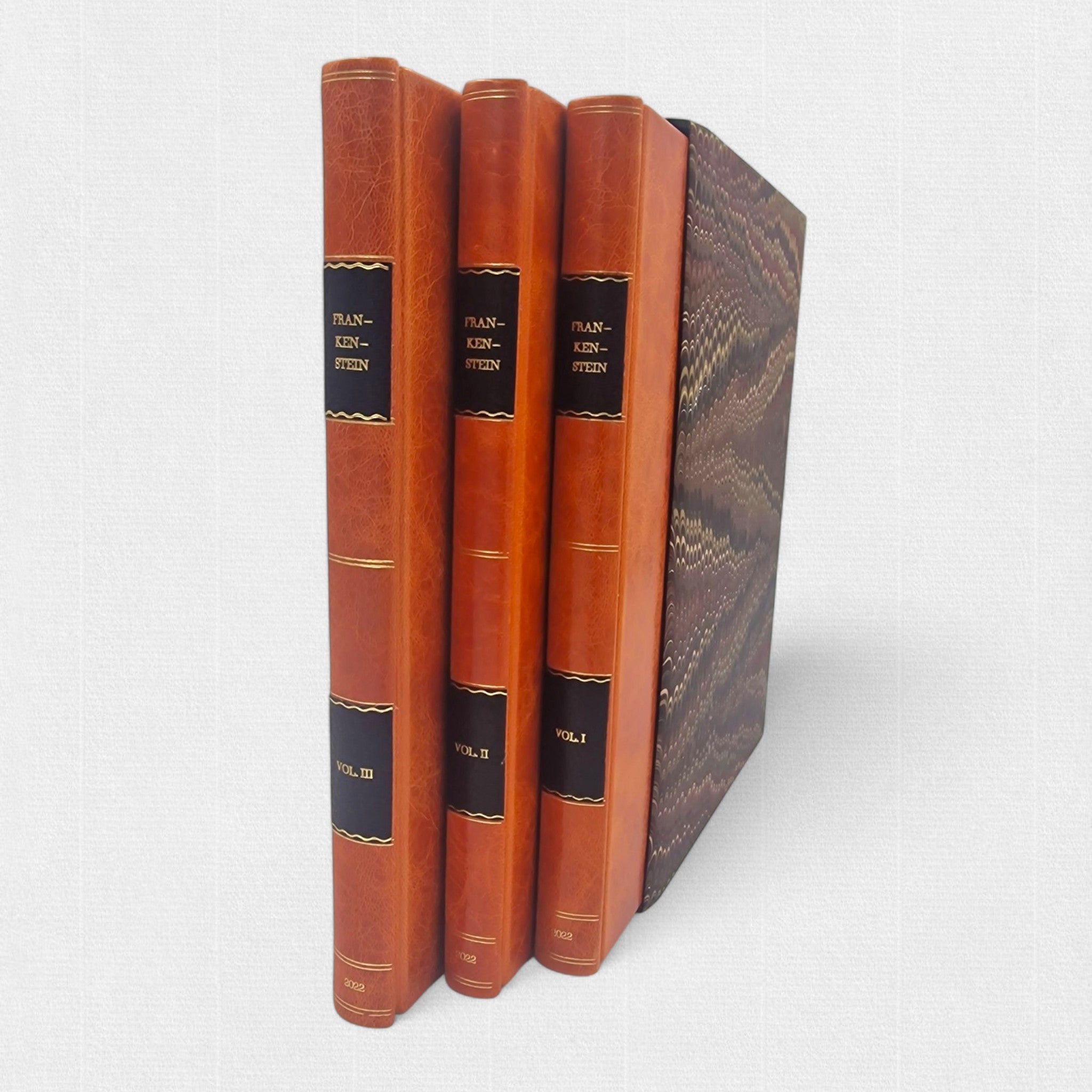 Spines of the three-volume Frankenstein fine press edition with gilt lettering and marbled slipcase.